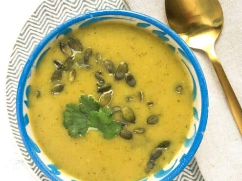 A bowl of zucchini, onion and sweet potato soup with pumpkin seeds on top